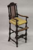 A CHILD'S 17TH CENTURY DESIGN OAK HIGH CHAIR with carved back and padded seat.