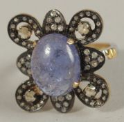 A SILVER GILT ORNATE DRESS RING set with an oval cabochon tanzanite and rose-cut diamonds. Tanzanite