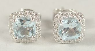 A PAIR OF HALLMARKED 18CT WHITE GOLD, BLUE TOPAZ AND DIAMOND CLUSTER EAR STUDS.