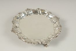 A SMALL GEORGE II SILVER WAITER with cast border, on three pad feet. 17cms diameter. London 1753.