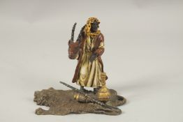A COLD CAST PAINTED ARAB MAN standing on a tiger rug. 14cms high.