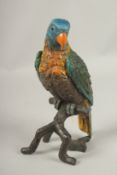 A LARGE PAINTED COLD CAST PARROT on a rustic branch. 28cms high.