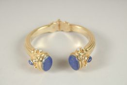 A HALLMARKED STERLING SILVER AND GILDED BANGLE, set with lapis and half pearls.