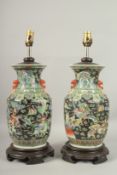 A PAIR OF CHINESE BLACK AND GREEN PORCELAIN LAMPS on circular wooden bases. Vases: 36cms high.