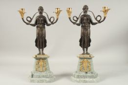 A PAIR OF REGENCY BRONZE TWO-LIGHT CANDLESTICKS, with a pair of classical female figures on a marble