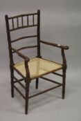 A FAUX BAMBOO COUNTRY ARM CHAIR with canework seat.