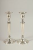 A PAIR OF SILVER CIRCULAR CANDLESTICKS on circular bases. 23cms high.