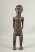 A NATIVE CARVED WOOD STANDING FEMALE FIGURE. 55cms high.