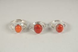 THREE SILVER AND AMBER RINGS.