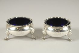 A PAIR OF GEORGE III CIRCULAR SILVER SALTS with sapphire blue liners, on three pad feet. London