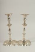 A PAIR OF GEORGE III SILVER CAST CANDLESTICKS by W. CAFE with cast shell bases, 26cms high. London