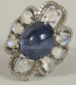 A LARGE DRESS RING set with a central oval cabochon dark blue sapphire, with surrounding oval