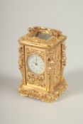 A SMALL ORNATE GILT METAL CARRIAGE CLOCK in an ornate case with female nudes. 6.5cms high.