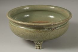 A 16TH CENTURY GREEN GLAZED DEEP CIRCULAR BOWL, raised on three lion feet. 15cm high, 32cm wide.