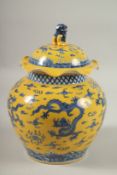 A CHINESE YELLOW GROUND BLUE AND WHITE DRAGON GINGER JAR AND COVER, 30cm high.