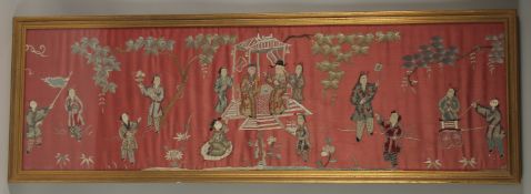 A LARGE CHINESE EMBROIDERED SILK PANEL, depicting figures, framed and glazed, 33cm x 110cm.