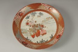 A JAPANESE KUTANI PORCELAIN CHARGER, painted with a central panel of figures and heightened with