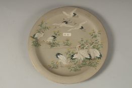 A JAPANESE ENAMELLED POTTERY DISH, depicting cranes and flora, the base with carved signature,