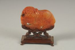 A GOOD CHINESE CARVED JADE DOG OF FO, 9cm long, 6cm wide, on a wooden stand.