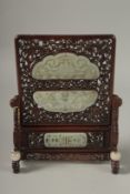 A PAIR OF SHAPED JADE PLAQUES INSET WITHIN A HARDWOOD FRAME, creating a carved wood table screen,