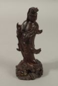 A CHINESE CARVED WOOD FIGURE OF GUANYIN, stood upon a beast with inset eyes and teeth, 15.5cm high.