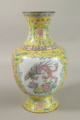 A CHINESE YELLOW GROUND ENAMELLED VASE, painted with a panel depicting an exotic bird and flora,