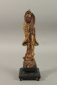 A CHINESE CARVED POTTERY FIGURE, mounted to a hardwood base, 35cm high.