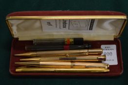 A group of gold and other propelling pens and pencils.