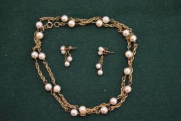 A gold and pearl necklace with pair of matching earrings.