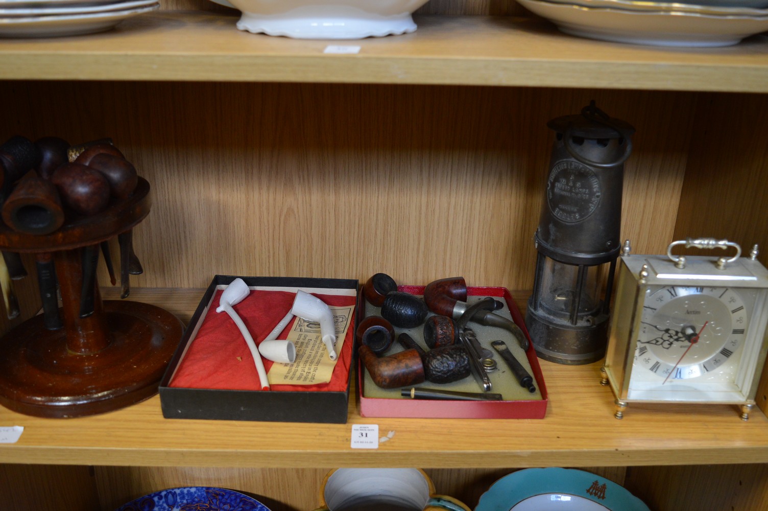 Various smokers pipes, a carriage clock and a miners lamp.