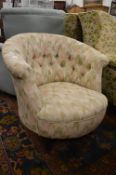 An upholstered horseshoe shaped bedroom chair.