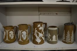 Five brown Jasperware jugs with sprigged decoration.