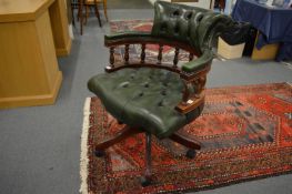 A green leather upholstered mahogany framed swivel office armchair.