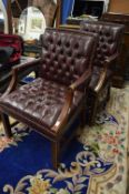 A pair of mahogany framed button burgundy leather upholstered open armchairs.