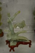 A Chinese carved jade group depicting birds on a branch, on a hardwood stand.