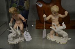 A pair of East German porcelain figures depicting young boys playing rabbits and dogs.