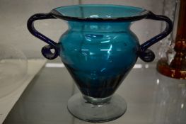 A blue glass twin handled pedestal vase.