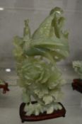 A Chinese carved jade group of a bird on flowering branches on a hardwood stand.