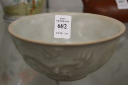 A Chinese celadon glazed bowl with moulded dragon decoration.