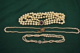 Various pearl necklaces with decorative clasps.