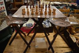 An unusual embossed leather chess table with folding stand together with a pair of matching stools