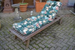 A teak garden lounger with cushion.