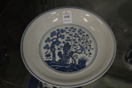 Chinese circular blue and white dish painted with a garden scene with trees.