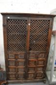 An old Eastern carved pine and lattice work two door cupboard.