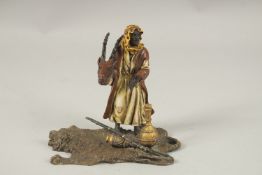 A COLD CAST PAINTED ARAB MAN standing on a tiger rug. 14cms high.