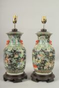 A PAIR OF CHINESE BLACK AND GREEN PORCELAIN LAMPS on circular wooden bases. Vases: 36cms high.