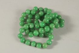 A LONG STRING OF JADE BEADS. 80cms long.