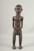 A NATIVE CARVED WOOD STANDING FEMALE FIGURE. 55cms high.