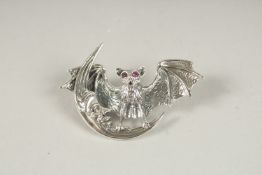 A SILVER RUBY EYE BAT BROOCH.