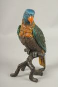 A LARGE PAINTED COLD CAST PARROT on a rustic branch. 28cms high.